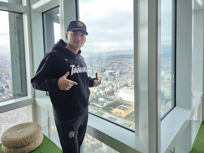朱育贤在台北101的89楼观景楼比出「Team Taiwan」手势，和下方的12强棒球赛中华队奇幻旅程的起点台北大巨蛋合照。（陈筱琳摄）