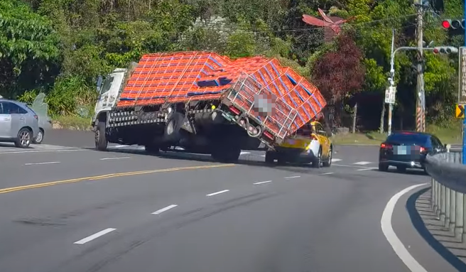 有大货车疑似煞车不及急闪，导致后斗鸡只掉落，还砸到停红灯的计程车。（图／翻摄自WoWtchout - 地图型行车影像分享平台）