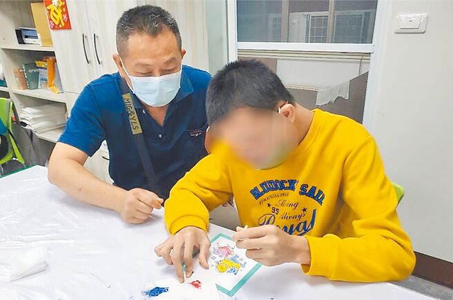 高市設置5處家托據點，家托員（左）鼓勵身障者阿家（右）透過繪畫訓練手部肌肉及配色。（高雄市社會局提供／林雅惠高雄傳真）