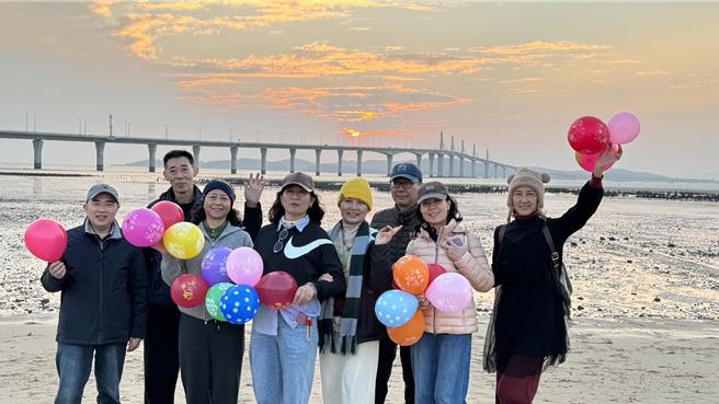 2024年金门的最后一道夕阳于下午5时30分日没，近百名陆客朝圣金门大桥绝美夕阳景色，齐聚于湖下海堤抢拍美景。（于家麒摄）