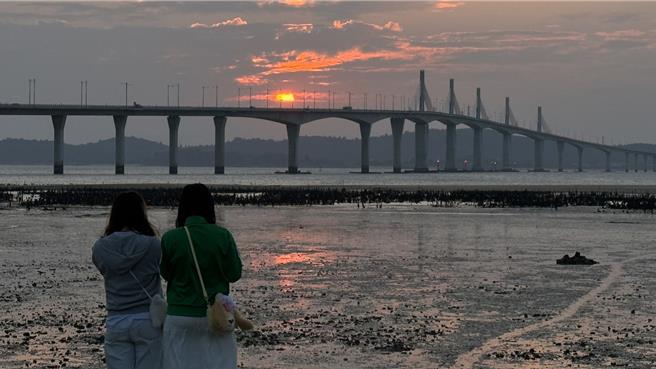 2024年金门的最后一道夕阳于下午5时30分日没，近百名陆客朝圣金门大桥绝美夕阳景色，齐聚于湖下海堤抢拍美景。（于家麒摄）