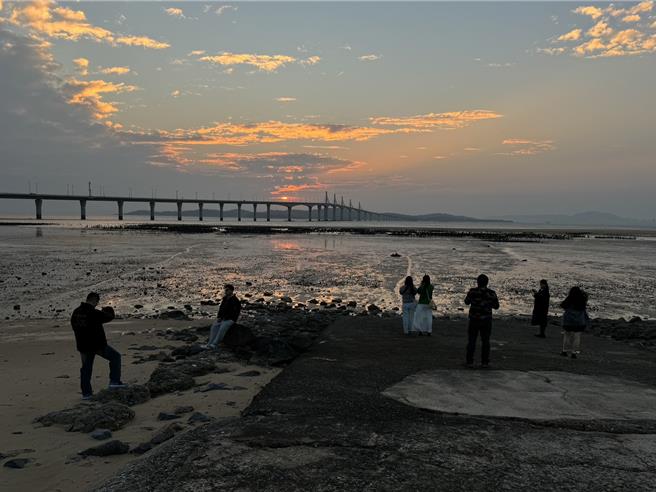 2024年金门的最后一道夕阳于下午5时30分日没，近百名陆客朝圣金门大桥绝美夕阳景色，齐聚于湖下海堤抢拍美景。（于家麒摄）