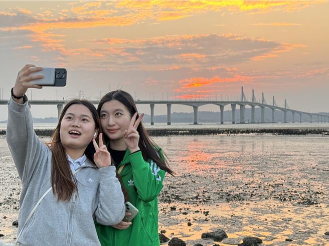 2024年金门的最后一道夕阳于下午5时30分日没，近百名陆客朝圣金门大桥绝美夕阳景色，齐聚于湖下海堤抢拍美景。（于家麒摄）