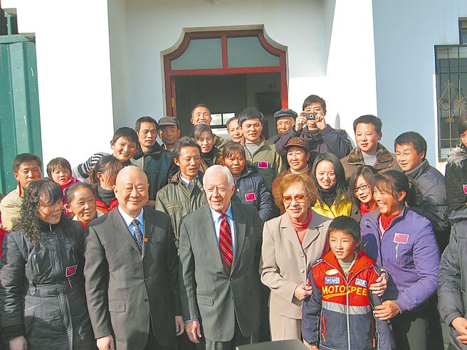 美国前总统卡特曾在2019年投书《华盛顿邮报》警告，美国若把中国视为「霸权挑战者」，这种思维很可能让两国陷入「当代冷战」。图为卡特（前排中）与李家大屋村村民合影。（中新社）