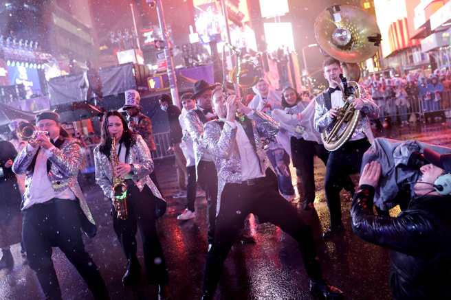 31日纽约下起大雨，时报广场上庆祝跨年的乐手冒雨热情表演。（路透社）