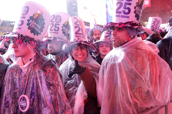 31日跨年夜纽约下起大雨，时报广场上庆祝跨年的民眾穿着雨衣等待倒数。（路透社）