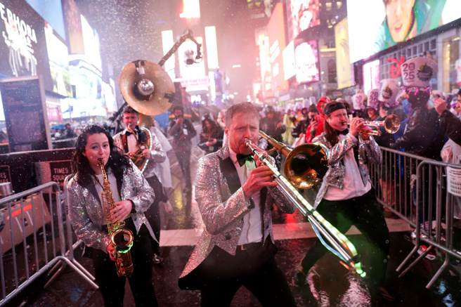 31日跨年夜纽约下起大雨，时报广场上乐手冒雨热情表演。（路透社）