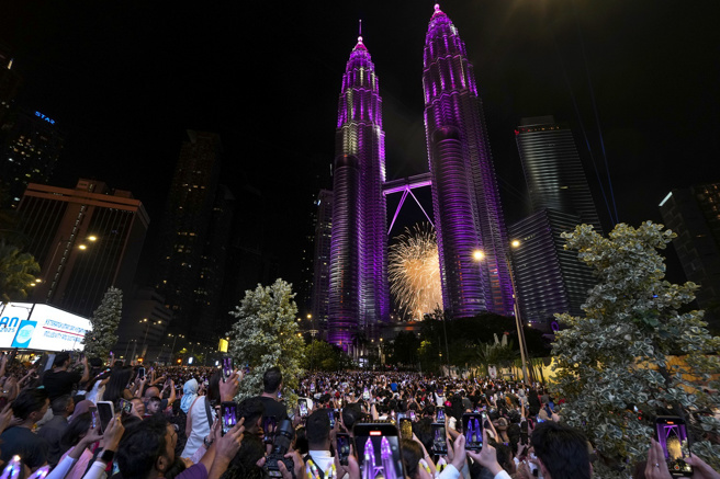 马来西亚民眾聚集观赏吉隆坡双子星大楼附近的烟火秀。（美联社）