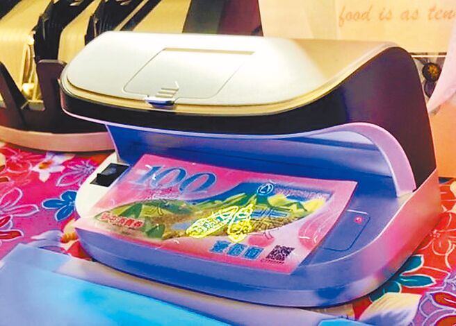 南投縣草屯鎮公所2日公布消費券樣式，每張面額為100元，正面在紫外光燈下出現一雙螢光草鞋。（楊靜茹攝）