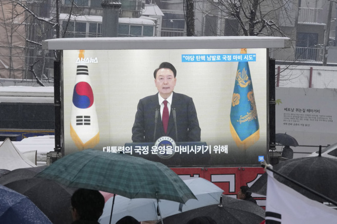 南韩总统尹锡悦因戒严遭国会弹劾停职，数度拒绝检方传唤调查。总统官邸外的挺引群眾5日围在电视萤幕前收看新闻报导。（资料照／美联社）