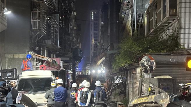 新北市三重区六张街一处建案开挖地下室，却不明原因在今（6）造成建案左右两侧、屋龄约40年的邻屋倾斜，即便工务局决议晚间拆除，但其中右侧的邻屋还是于晚间8时45分倒塌，而左侧房屋将待路面碎石清理完善后即刻展开拆除作业。（贺培晏摄）