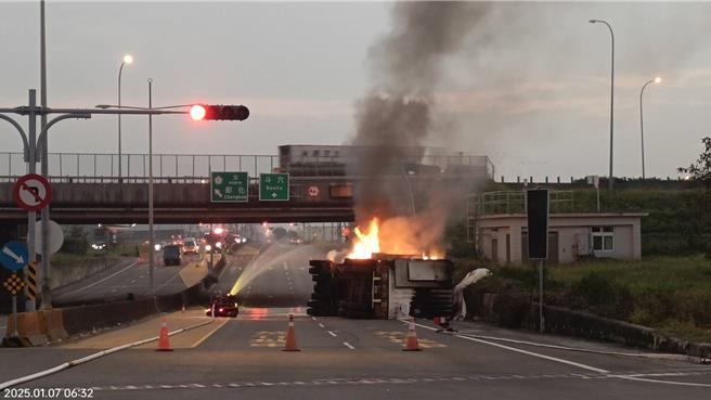 一辆载运锂电池大货车昨翻覆翻覆在联外道路上，今天清晨突然起火，暂时只能用机器人灌水。（民眾提供）