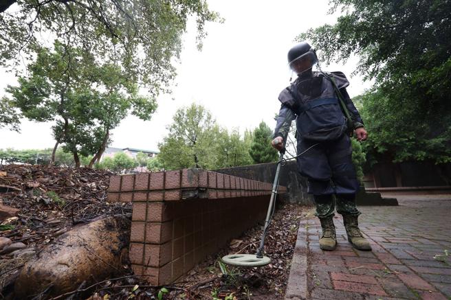  为探测正确位置，须依据声音的急促颤音声，逐次缩小侦测范围，以手持搜索杆持续进行精确扫雷探测。（记者袁铭骏摄）