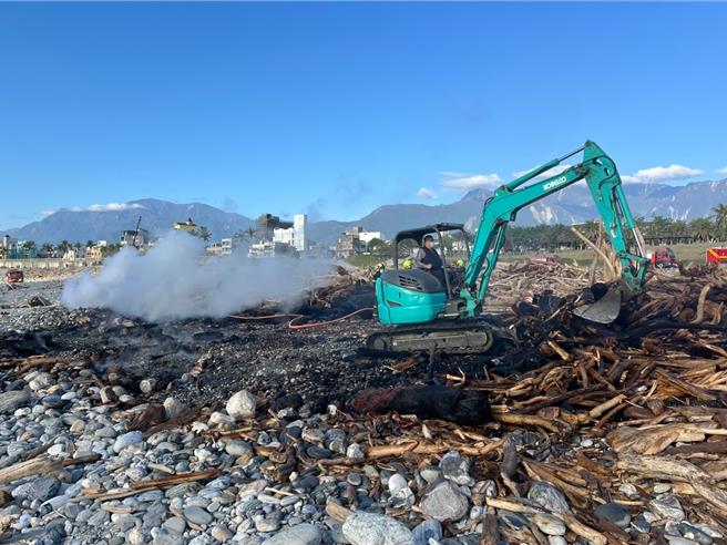 花蓮市北濱海灘漂流木起火燃燒，義消特搜大隊總幹事顏勝裕協助下，利用重機械怪手移除重木滅火。（花蓮縣消防局提供／王志偉花蓮傳真）