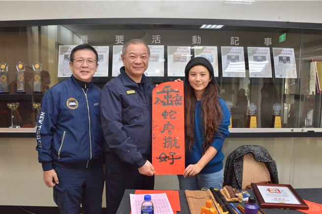 中国书法学会秘书崔毅老师（右一）现场书写「出入平安、蛇么拢好」。（新北市警察局提供）