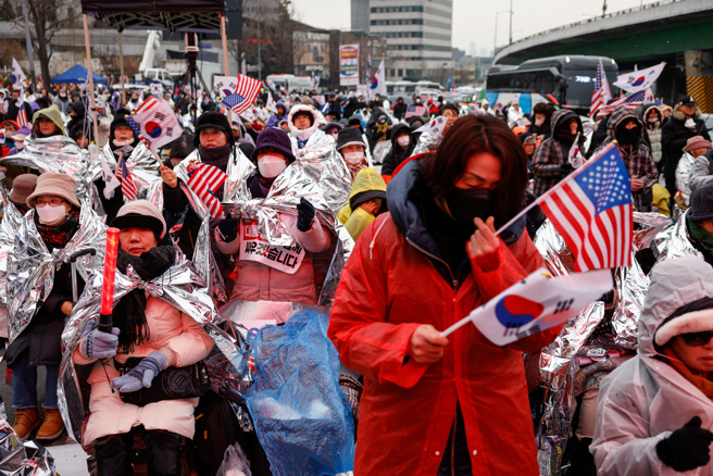 2025年1月13日，尹锡悦的支持者手持美国和韩国国旗，在韩国首尔官邸附近支持被弹劾的韩国总统尹锡悦。（路透社）