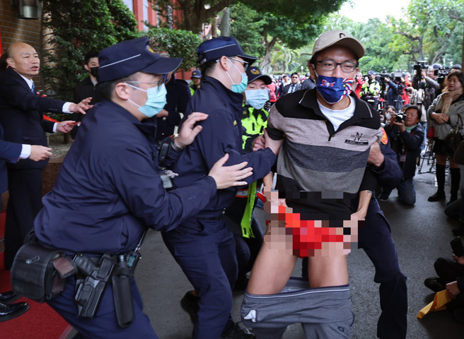 立法院长韩国瑜（左）17日在院门口发送春联，有民眾领完春联后，突然大喊「韩国瑜毁宪乱政」并脱裤抗议，立即遭驻卫警架离。（姚志平摄）
