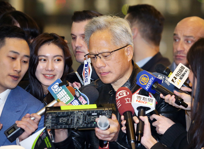 輝達（NVIDIA）執行長黃仁勳（中）17日出席台灣分公司尾牙，受訪時還不忘替粉絲簽名。（范揚光攝）