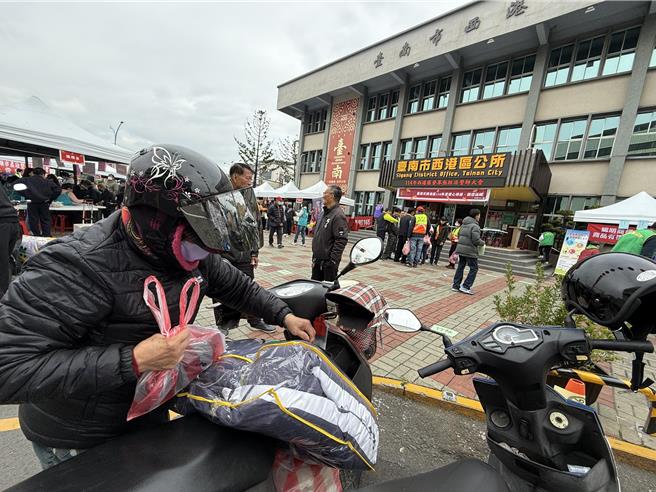 西港区公所发放物资，寒冬送暖，受助户收的物资多到载不完。（宝智华摄）