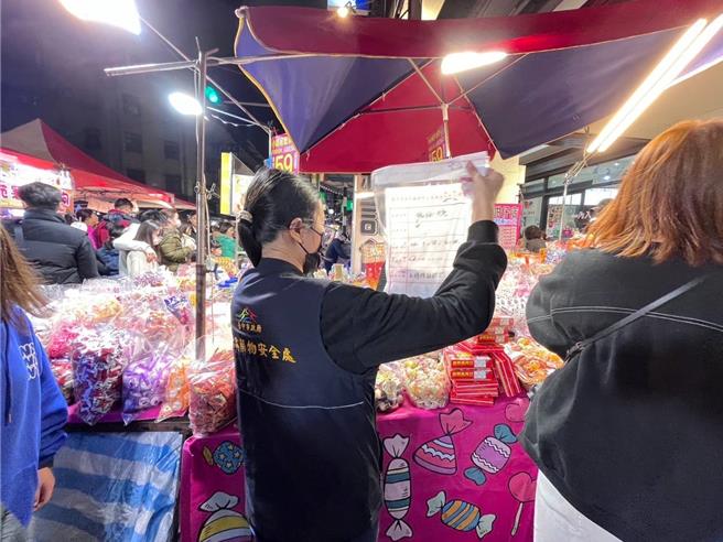 台中食安處稽查員到天津商圈年貨大街，查獲逾期糖果，現場責令業者下架。（台中市食安處提供／馮惠宜台中傳真）