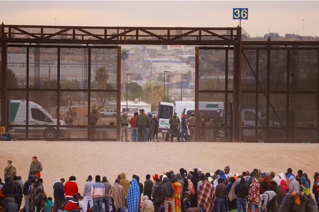 图为墨西哥华雷斯城，移民越过里奥布拉沃河后站在边境墙附近，准备向美国边境巡逻人员自首。（路透社）