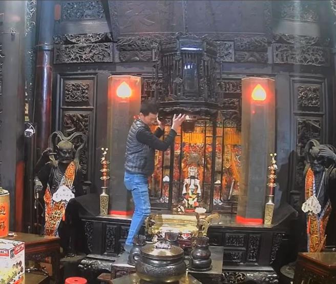 嘉义县21日凌晨发生强震，云林县北港朝天宫正殿上方悬吊的万年香火灯不断摇晃，庙方人员急忙爬上神桌用双手护住香火灯，幸好有惊无险。（民眾提供／张朝欣云林传真）