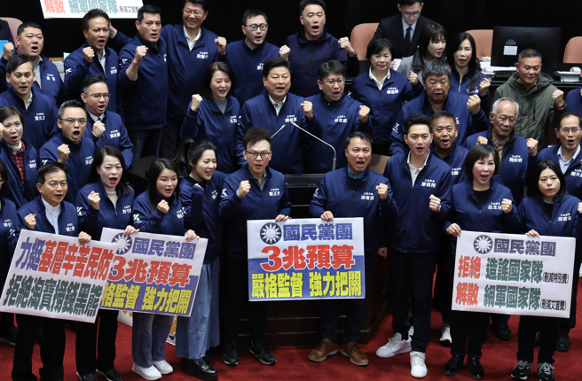 立法院21日院會三讀通過114年度中央政府總預算案，民進黨立委手持標語抗議藍白亂刪預算，並在議場內合影高喊口號。（資料照／姚志平攝）