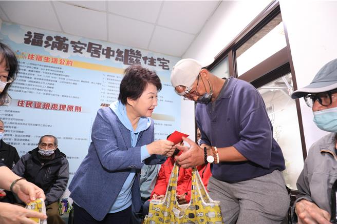 過年將屆，台中市長盧秀燕（左）於26日到西區「福滿安居中繼站」探視街友，送上物資、年夜飯及小紅包，祝福街友新年快樂。（張妍溱攝）