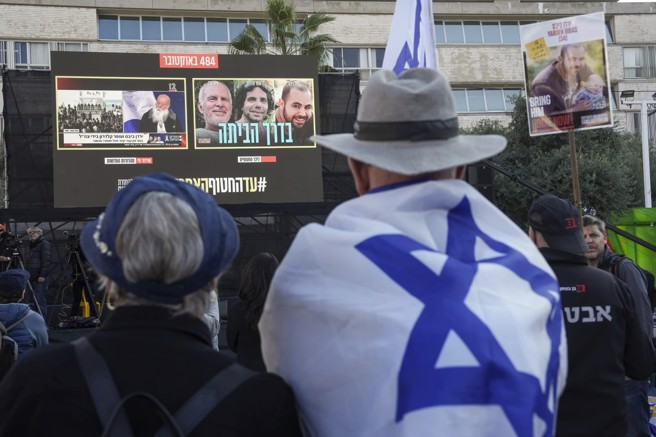 以色列特拉維夫街頭，人們關注著3名以色列人的釋放過程，這三人左起分別是美籍以色列人西格、53歲的卡德隆，一家四口都遭綁架的比巴斯。(圖/美聯社)