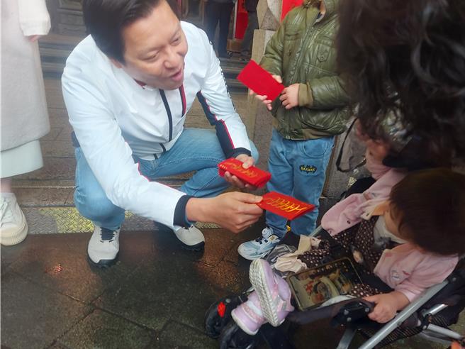 新北市副市长朱惕之2日在新庄宫庙发放福袋给小朋友。（张铠乙摄）