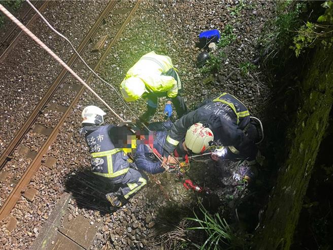 简姓男子自撞护栏，跌落铁轨旁，消防人员以吊挂方式救援。（新北市消防局提供）