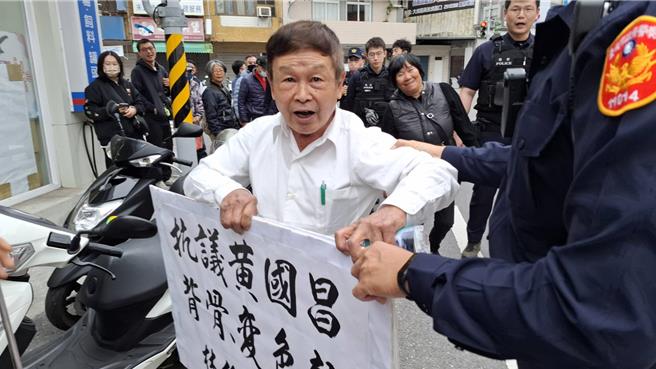 台南市中西区小西门里长曾俊仁也是民进党台南市立委林俊宪后援会干部，2日持标语到民眾党台南市党部抗议黄国昌，遭警方隔开支持者。（程炳璋摄）