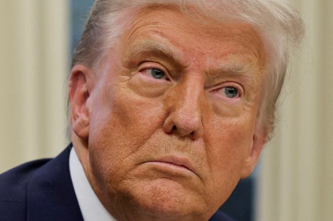 美国总统川普1月31日在白宫椭圆形办公室签署行政命令的神情。（路透）