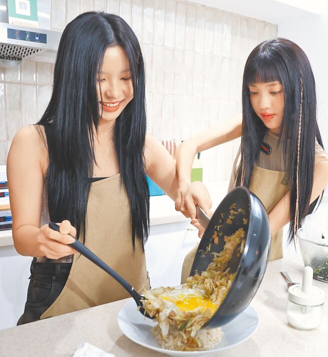 AYEON（左）與采甄把炒熟的高麗菜和洋蔥加蛋後倒在糙米飯上。 （陳俊吉攝）