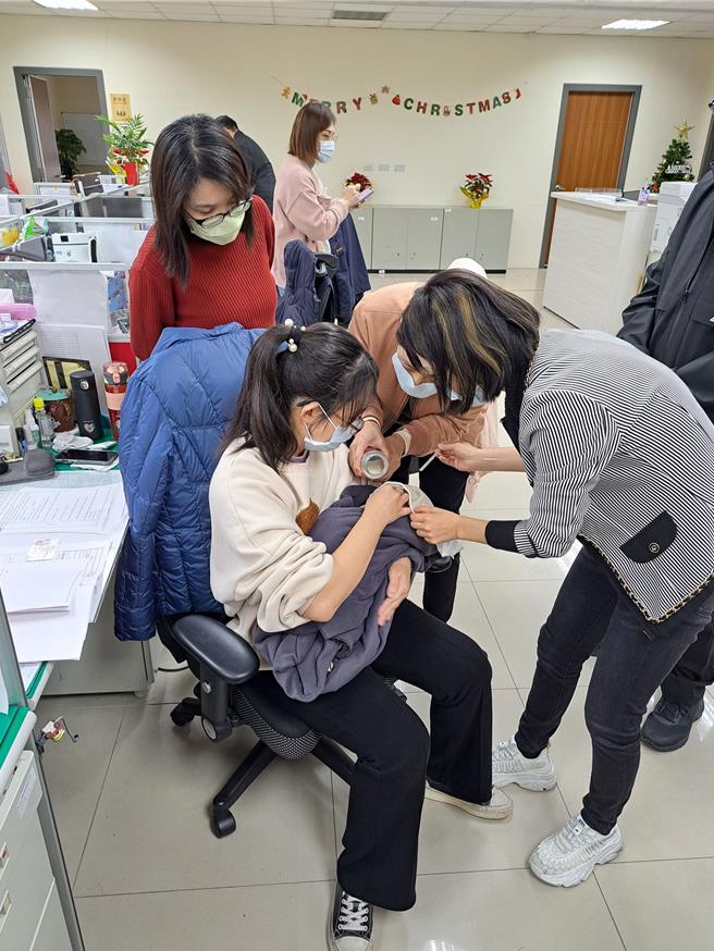 妇幼队警员曾英绫冲泡奶粉喂食飢肠辘辘的新生儿，热心同仁在旁协助。（台中市警察局提供）