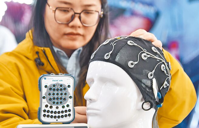业界报告指出，预计2030年脑机晶片医疗应用市场规模达400亿美元。图为首届匯爱科技展，工作人员展示脑机接口技术的康復设备。（新华社）