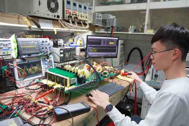 邱煌仁特聘教授研究团队学生检测三相换流器，此技术可应用于不断电系统与电动车充电系统，将插头提供的直流电转换为电器使用的交流电，为电器或电动车提供稳定可靠的供电支持。（照片/臺湾科技大学提供）