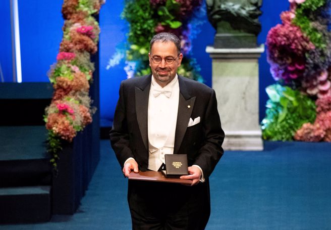 艾塞默魯於2024年12月10日在瑞典斯德哥爾摩音樂廳舉行的諾貝爾獎頒獎典禮上與獎項合影。（圖／路透）