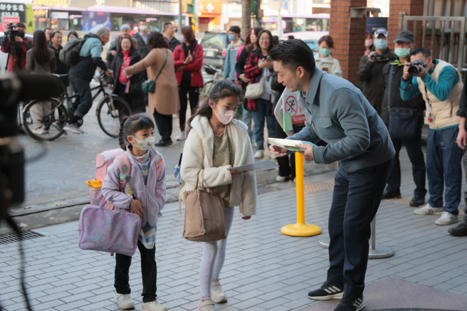 台北市长蒋万安（前右）11日出席铭传国小开学日活动，发放开学礼给踏入校园的学童。（郭吉铨摄）