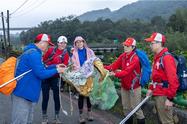參與民眾手持長夾與垃圾袋，沿步道拾起天燈殘骸及垃圾。（新北市觀旅局提供）