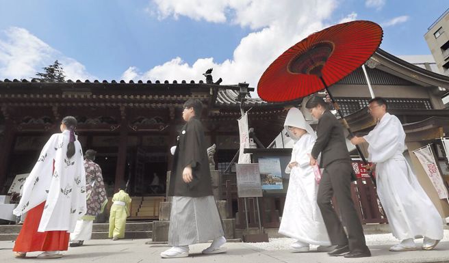 圖為新婚夫婦在東京淺草神社舉行的傳統婚禮儀式上接受護送。（資料照／美聯社）