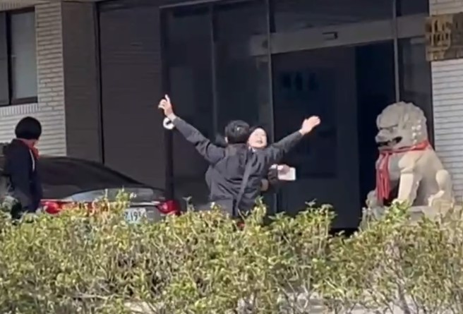 林岱樺與幹員在南機站門口爆拉扯，一高舉標語激動喊「政治、司法干預初選」遭阻擋。（民眾提供）