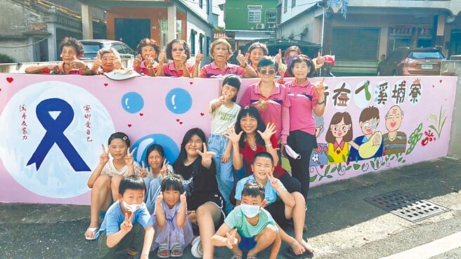 大寮區溪寮里居民致力預防家庭暴力，家門外的圍牆無償提供使用，由溪寮國小學生、社區居民及長輩共同參與著色，有世代共融溫馨和睦的四代同堂圖，還有重要的紫絲帶，作為社區驅逐暴力的代表意象。（溪寮社區發展協會提供／洪靖宜高雄傳真）