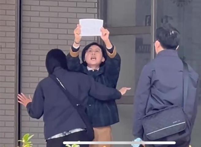 林岱桦20日到调查局南机站时举抗议字条，调查员企图阻挡。（民眾提供／郭良杰高雄传真）