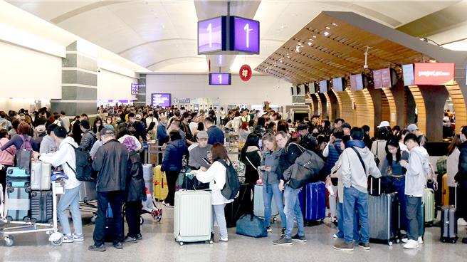 在桃机第一航厦内，出国旅客正在排队办理报到手续。（范扬光摄）