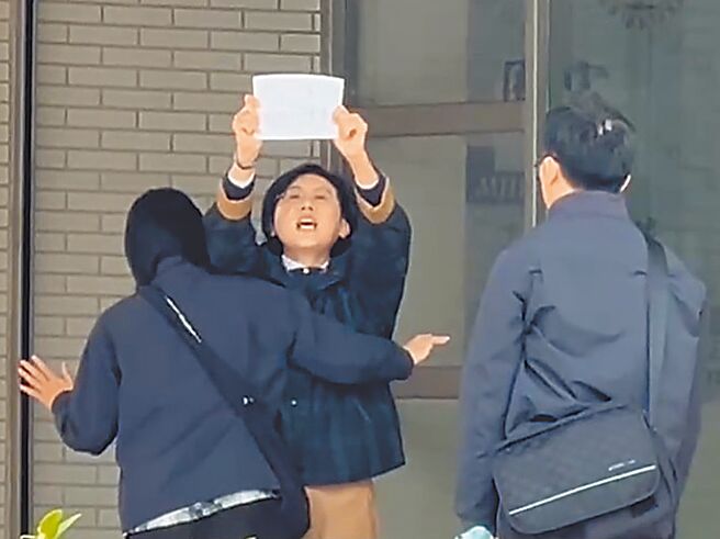 林岱桦2月20日到调查局南机站下车时，转身高举预备的字条，大喊「政治干预司法，司法干预初选」。（民眾提供／郭良杰高雄传真）