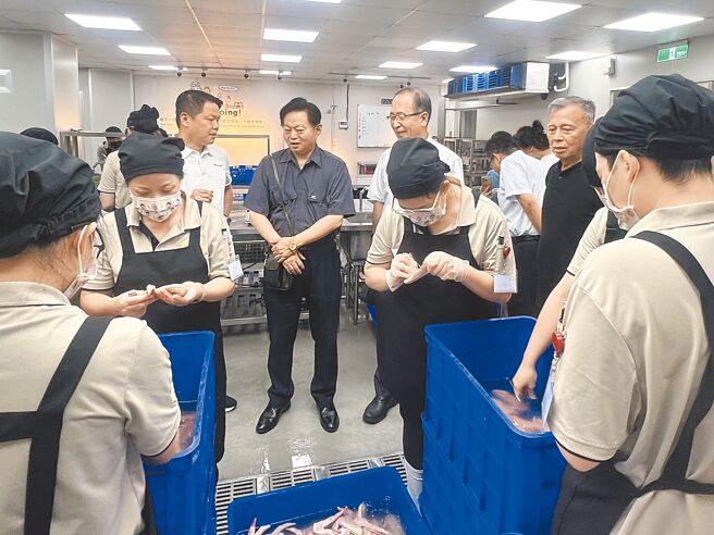 矯正署署長周輝煌（後排中，灰衣者）視察助更計畫，由參與企業龍行天下集團執行長黃偉峸（後排左，白衣者）解說。（照片提供龍行天下集團）