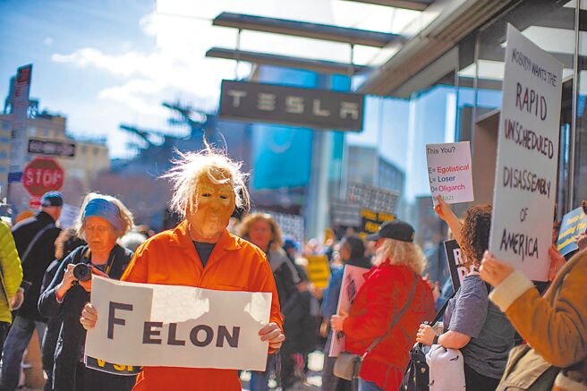 1日，美国纽约市，一名戴着代表美国总统川普的面具的男子在特斯拉店外参加抗议活动。（路透）