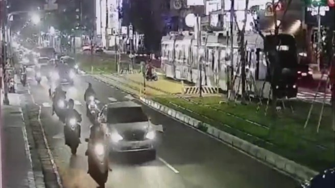 一名家长骑乘普通重型机车，违规载着两名孩童（俗称「三贴」），行经大顺路、富民路口时，竟无视交通号志，直接停在轻轨轨道上等待左转。（图／简铭柱翻摄）