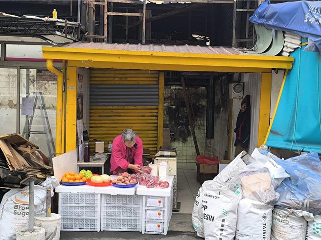 廖姓水果攤老闆娘仍在焚毀的店面前擺攤。（李京昇攝）